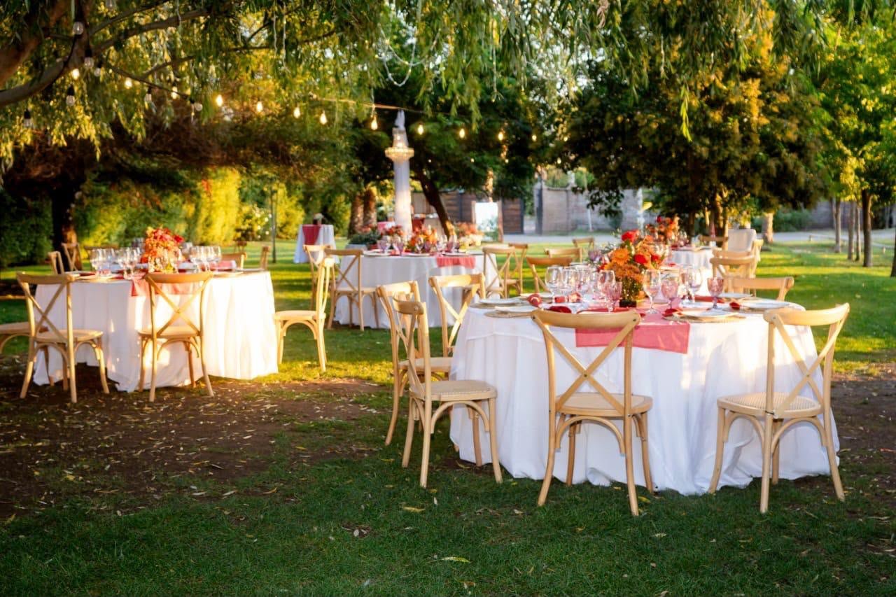 Mesas redondas en el jardín al atardecer bajo los árboles